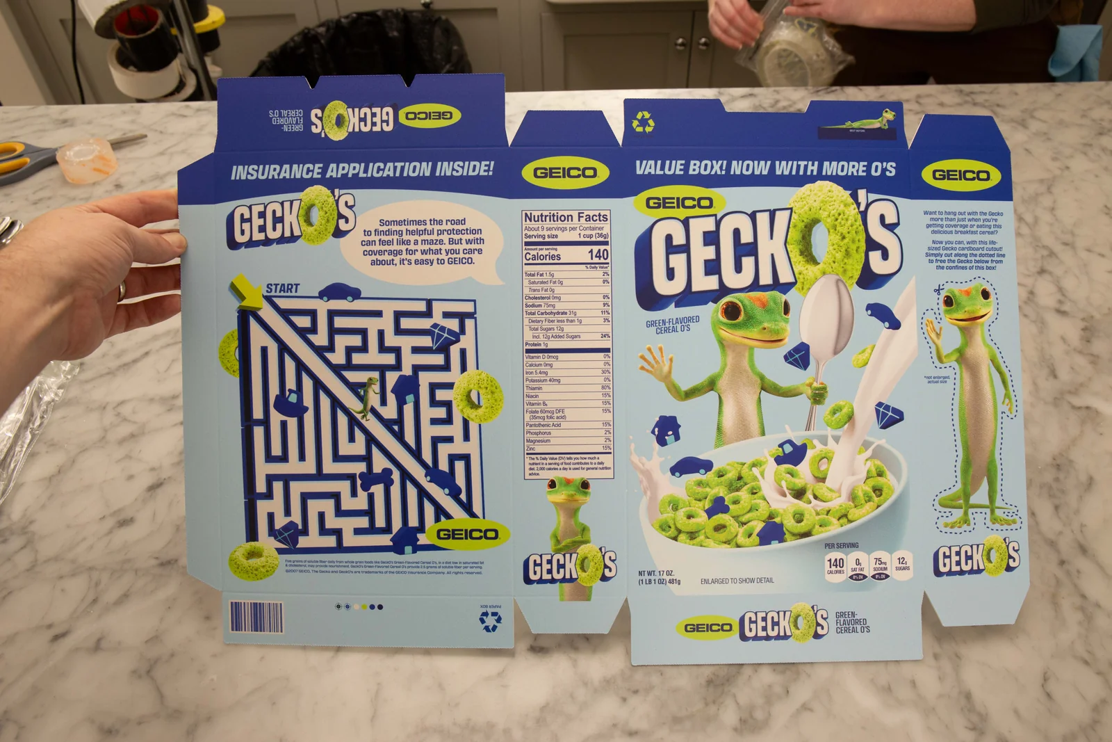 Printed flat cereal-box packaging held open on the kitchen set.