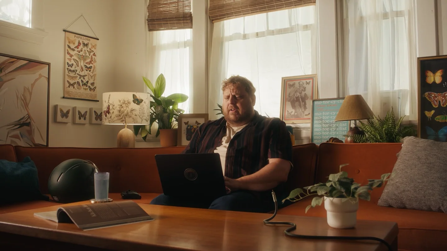 Wide living-room campaign frame with a man and Cable Snake on a coffee table.